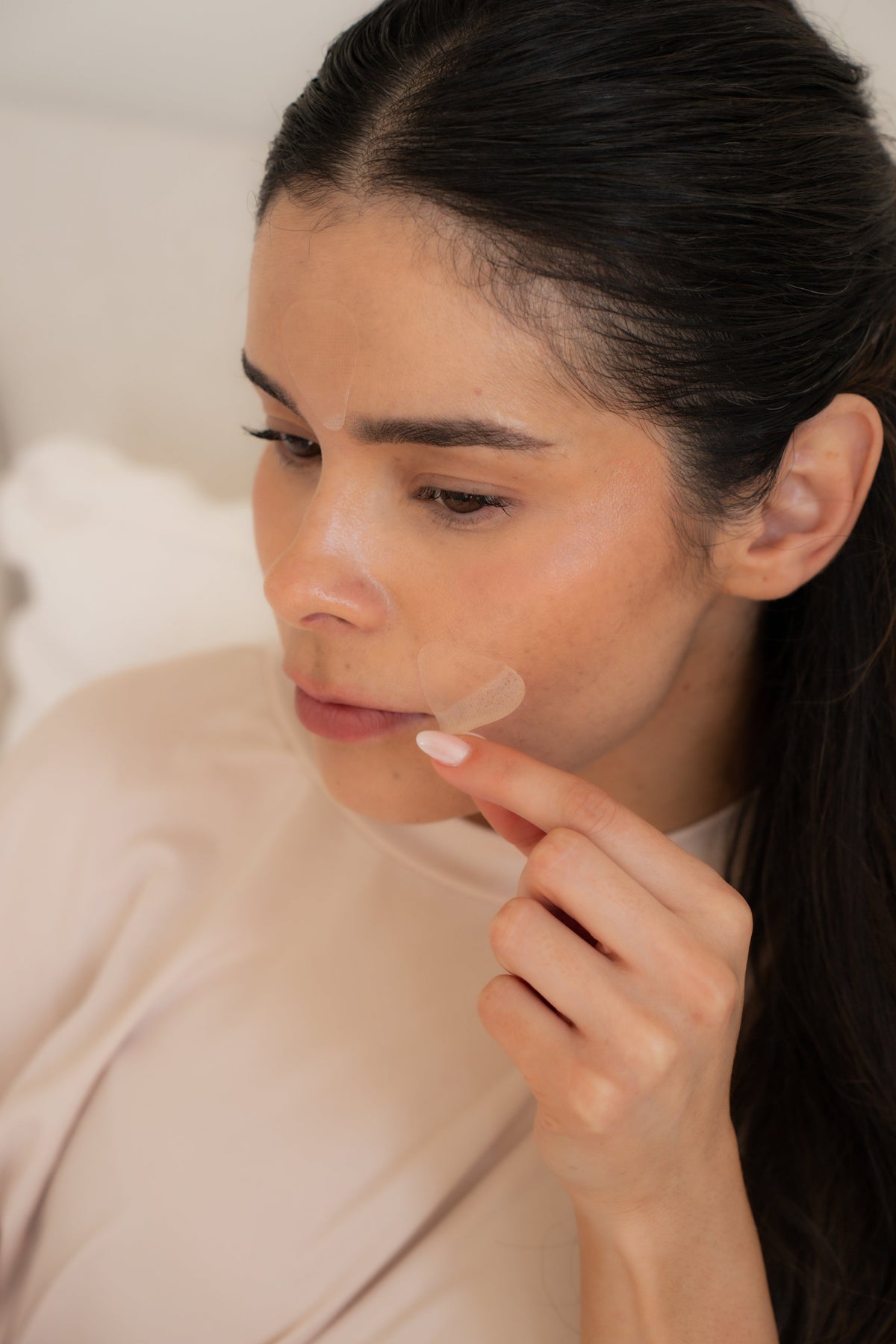 Woman smoothing a clear Toute Nuit patch over a line beside her mouth